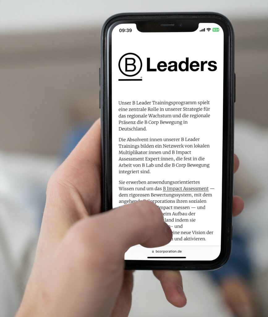 Smarphone Screen in einer Hand mit einem Text mit der Überschrift B Leaders